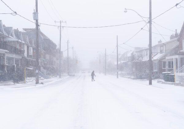 A man crosses a road during a snowstorm in Toronto on Dec. 23, 2022. A winter storm warning is in place for most of southern Ontario. (Arlyn McAdorey/The Canadian Press)