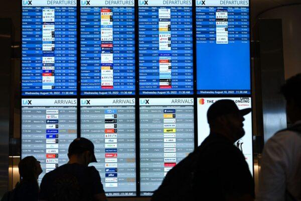 Passengers look at flight departure information boards in the West Gates expansion area at Los Angeles International Airport (LAX) in Los Angeles, on Aug. 10, 2022. (Patrick T. Fallon/AFP via Getty Images)