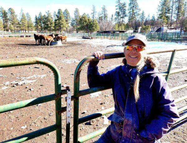 Ranch owner Molly Wisecarver stands by the corral where she keeps nine recently adopted wild horses in Williams, Ariz., on Dec. 23, 2022. (Allan Stein/The Epoch Times)