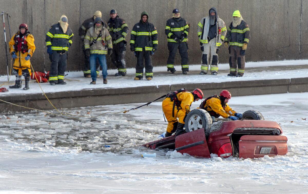 Kansas City fire department rescue workers work to recover a minivan that went into Brush Creek in Kansas City, Mo., on Dec. 22, 2022. Police say the driver lost control of the minivan on an icy street and the vehicle went down an embankment and overturned before submerging in Brush Creek. The driver was pulled from the creek but died later at a hospital. (Nick Wagner/The Kansas City Star via AP)