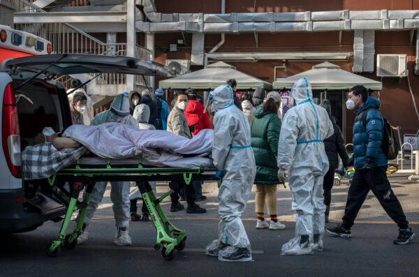 Medical workers wear PPE as they arrive with a patient on a stretcher at a fever clinic in Beijing, on Dec. 9, 2022. (Kevin Frayer/Getty Images)