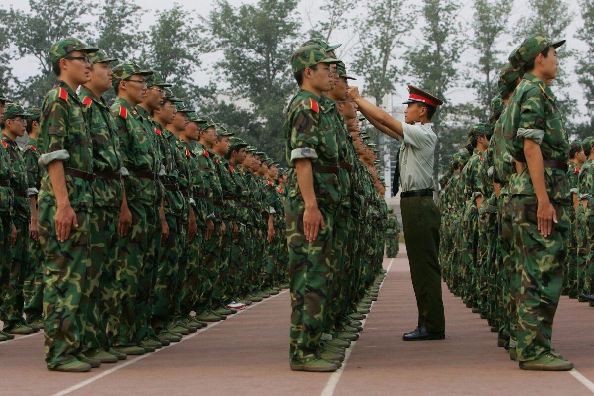 A military officer adjusts a student's cap during military training at the Tsinghua University in Beijing on Sept. 7, 2006. (China Photos/Getty Images)