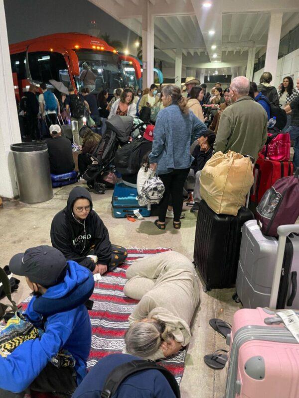 Passengers await transport at the airport in Cancun, Mexico, in the early hours of Dec. 25, 2022, after their delayed flight home to Canada was cancelled once again. (Hina Itsaso/The Canadian Press)