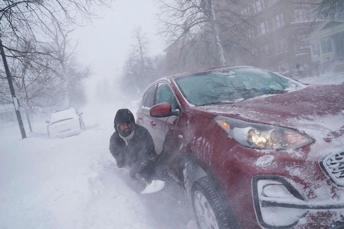 Gamaliel Vega tries to dig out his car on Lafayette Avenue after he got stuck in a snowdrift about a block from home while trying to help rescue his cousin, who had lost power and heat with a baby at home across town during a blizzard in Buffalo, N.Y., on Dec. 24, 2022. (Derek Gee/The Buffalo News via AP)