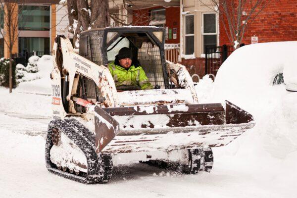 A man uses Bobcat to remove snow from around a trapped car following a winter storm in Buffalo, N.Y., on Dec. 27, 2022. (Lindsay DeDario/Reuters)