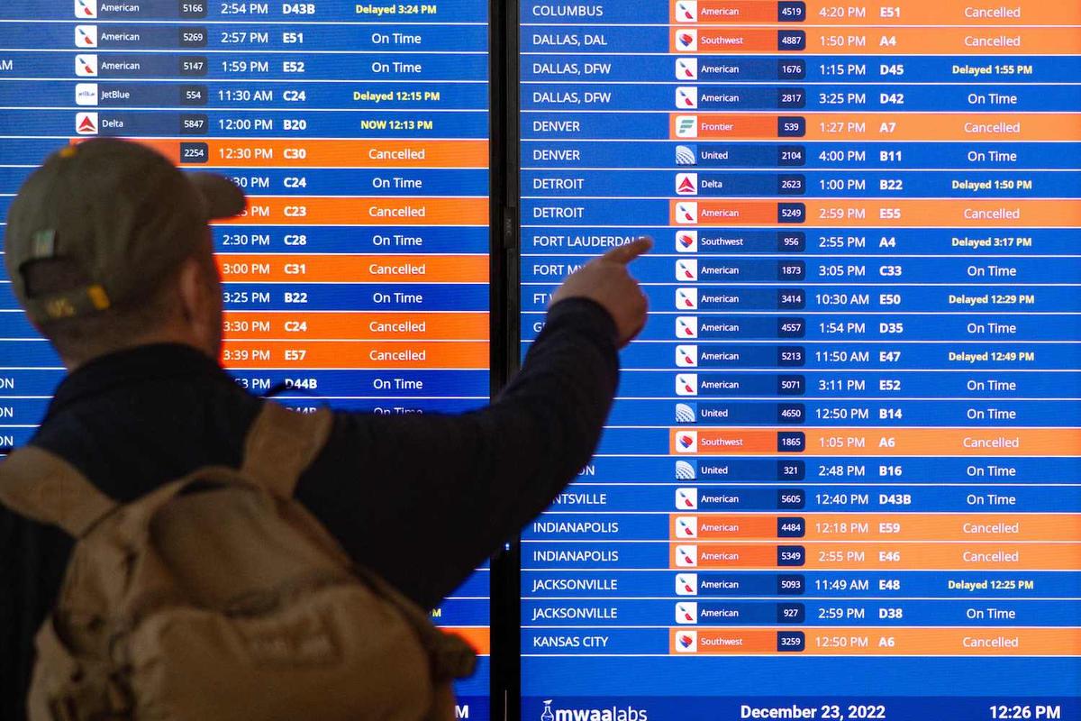 A traveler looks at an information board showing flight cancellations and delays at Reagan National airport during a winter storm ahead of the Christmas holiday in Arlington, Va., on Dec. 23, 2022. (Mandel Ngan/AFP via Getty Images)
