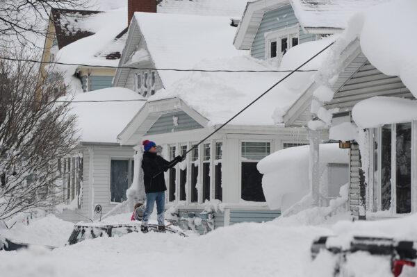 A man attempts to clear his roof of snow on Dec. 26, 2022 in Buffalo, New York. The historic winter storm Elliott dumped up to four feet of snow on the area leaving thousands without power and 27 confirmed dead in the city of Buffalo. (John Normile/Getty Images)