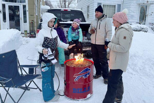 A group of neighbors gather around a fire pit on Culver Road after clearing snow in Buffalo, N.Y., on Dec. 26, 2022. (Carolyn Thompson/AP Photo)