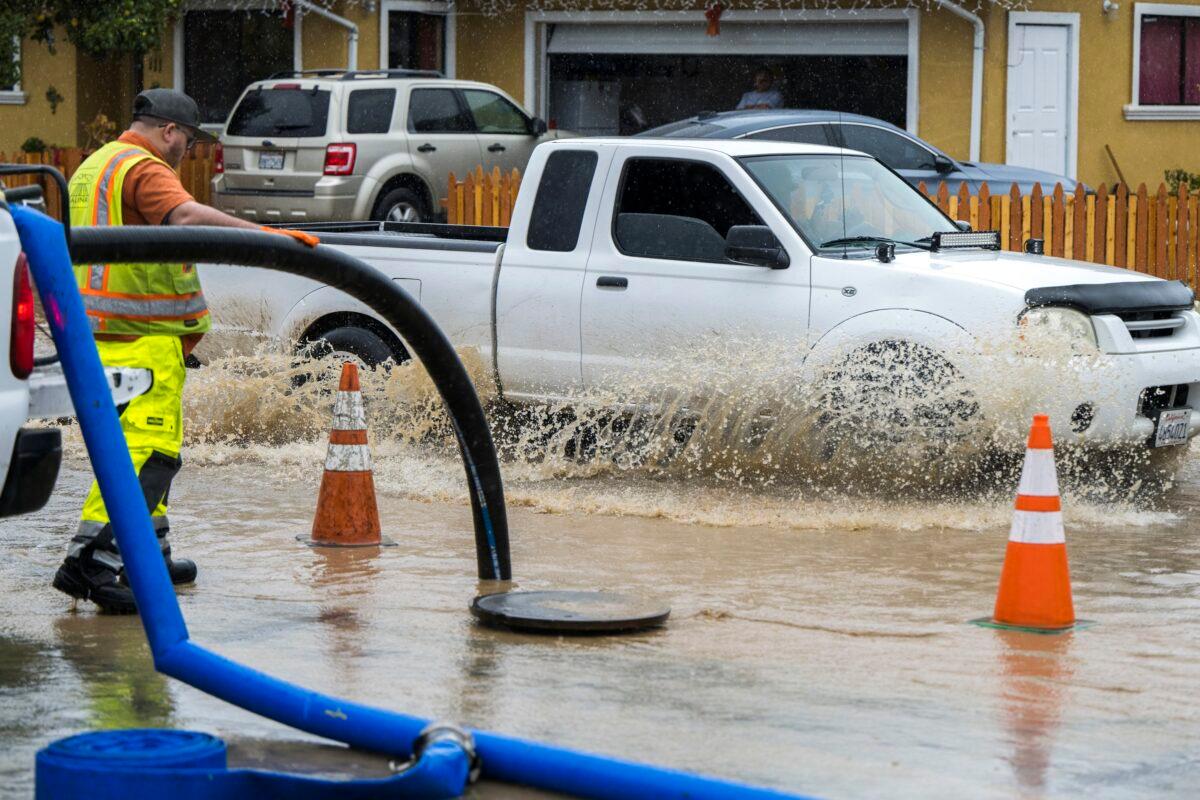 A member of public works clears a flooded storm drain on E Bolivar Street in Salinas, Calif., on Dec. 27, 2022. (Nic Coury/AP Photo)
