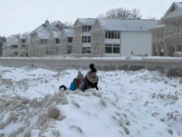 Children play on the beach in front of houses engulfed in ice in Crystal Beach, Fort Erie, Ont., on Dec. 25, 2022. (Courtesy of Tracey Cotton)