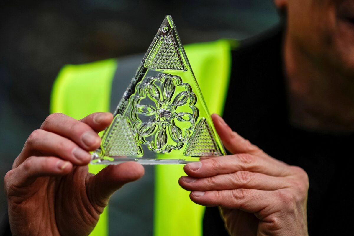 A workers holds up one of the new Waterford Crystal triangles featuring this year's "Gift of Love" design on the Times Square New Year's Eve Ball on the roof of One Times Square in Manhattan, New York, on Dec. 27, 2022. (Eduardo Munoz/Reuters)
