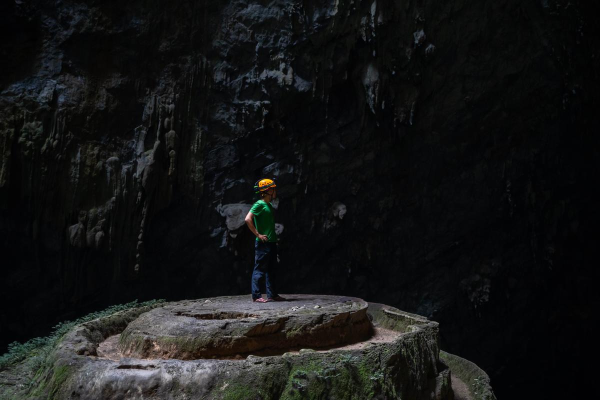 A cave explorer looks on from atop a massive stalagmite in the cave. (kid315/Shutterstock)