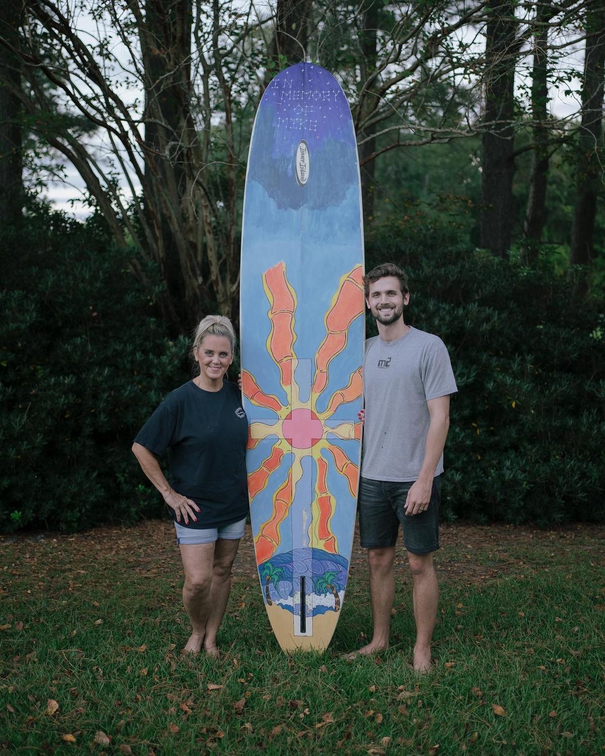 Troy and Robin with the special surfboard painted in memory of Mikell, which the family had lost in 2016 and Troy tracked down in 2020. (Courtesy of <a href="https://www.instagram.com/troybedenbaugh/">Troy Bedenbaugh</a>)