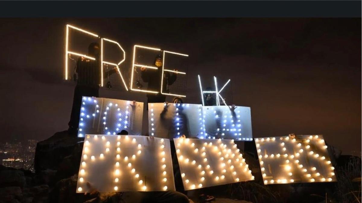 More than a dozen Hong Kong people holding LED luminaires and electronic candles to display the words "Free HK political prisoners" atop Lion Rock in Hong Kong on Dec. 31, 2022. (Hui Tat /The Epoch Times)