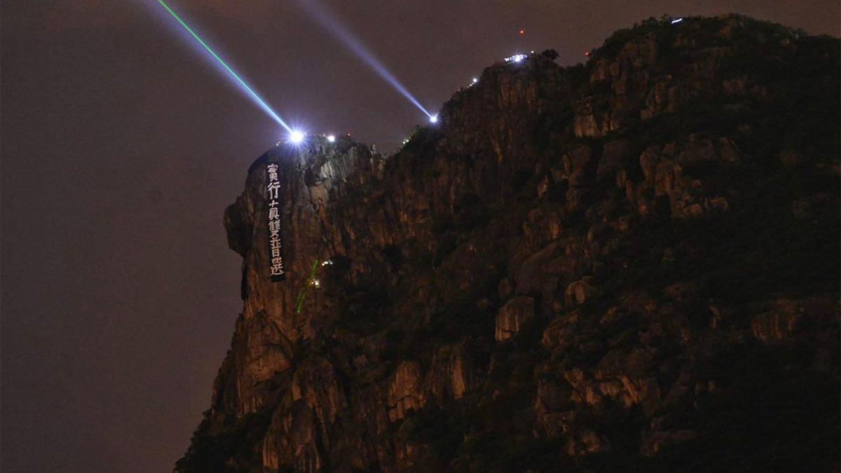 Hong Kong citizens from Lion Rock Hill and Victoria Peak flashed lights at each other in unison with laser pointers and flashlights. They hurled down a banner calling for "Bona Fide Universal Suffrage (for the positions of Chief Executive and the Legislative Council)" on the Lion Rock in Hong Kong on Sept. 13, 2019. (Sung Pi-lung/The Epoch Times)