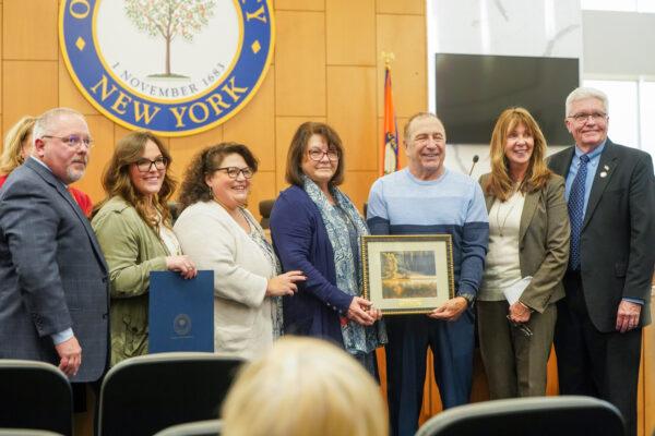 (L–R) Tom Faggione, Rebbeca Hulse, Denise Hulse, Pricilla Gould, Jonathan Gould, Ann Marie Maglione, and Barry Cheney at a ceremony awarding the Senior of the Year at the county government in Goshen, N.Y., on Dec. 1, 2022. (Cara Ding/The Epoch Times)