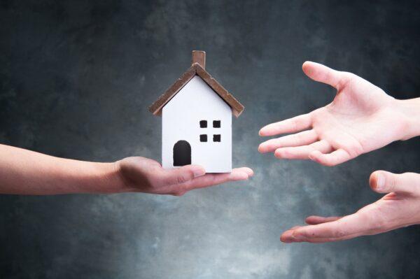 Undated image of hands reaching out to a house ornament. (beeboys/Shutterstock)