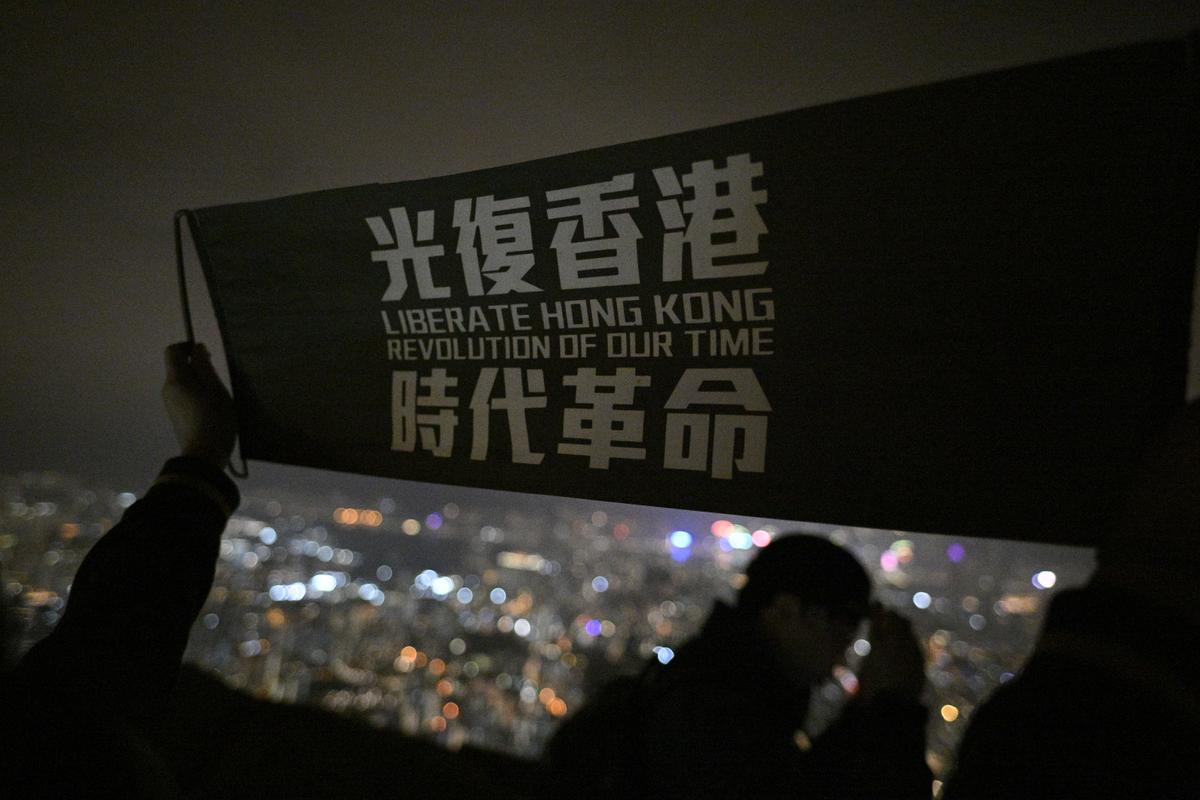 Hong Kong people holding flags and yelling slogans “Liberate Hong Kong, Revolutions of Our Times,” atop Lion Rock in Hong Kong on Dec. 31, 2022. (Hui Tat/The Epoch Times
