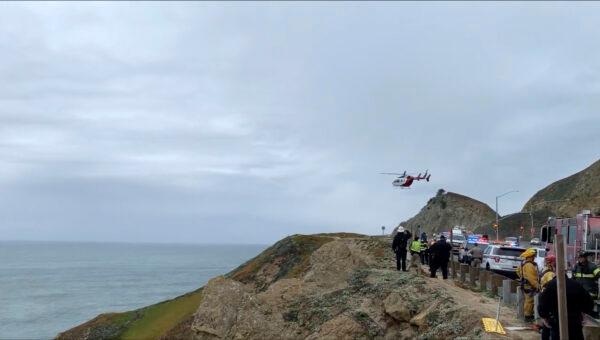 In this image from video provided by Cal Fire San Mateo, Santa Cruz Unit, emergency personnel respond to the scene after a Tesla plunged off a cliff along the Pacific Coast Highway on Jan. 2, 2023, in Northern California, near an area known as Devil's Slide, leaving four people in critical condition, a fire official said. (Cal Fire San Mateo—Santa Cruz Unit via AP)