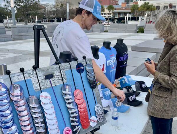 Jon Youngblood sells a T-shirt and buttons to Celia Gruss just outside the site of the ceremony to swear in Fla. Gov. Ron DeSantis for his second term in Tallahassee, Fla. on Jan. 3. (Nanette Holt/The Epoch Times)