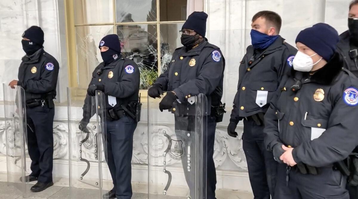 U.S. Capitol Police guard a broken window smashed in by a rioter on the east side of the Capitol on Jan. 6, 2021. (Bobby Powell/Special to The Epoch Times)