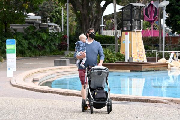 A man is seen going for his morning walk holding his baby in Brisbane, Australia, on Sept. 29, 2021. (Bradley Kanaris/Getty Images)