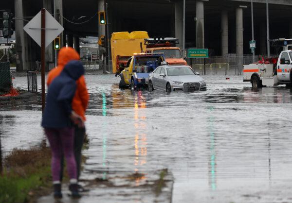 People look on as a tow truck pulls a car out of a flooded intersection in Mill Valley, Calif., on Jan. 4, 2023. (Justin Sullivan/Getty Images)
