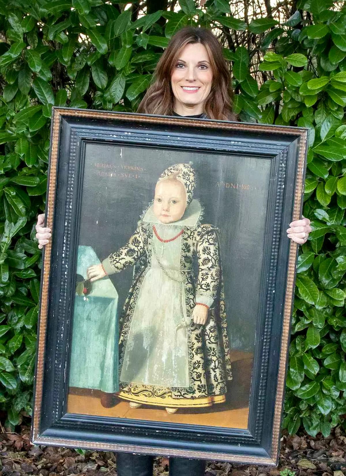 Helen Smith, of Hansons, with the portrait of a "miniature adult" in an elaborate full-length gown. (SWNS)