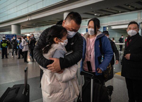 A man hugs his daughter as he arrives from a flight to the international arrivals area of Beijing Capital Airport on Jan. 8, 2023. (Kevin Frayer/Getty Images)