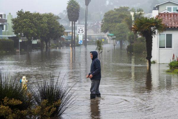A man wades through a flooded street in the Rio Del Mar neighborhood of Aptos, Calif., on Jan. 9, 2023. (Nic Coury/AP Photo)