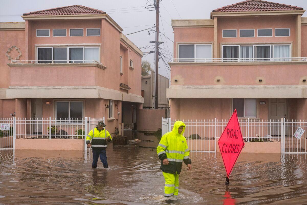A cleaning crew walks through floodwaters in the Rio Del Mar neighborhood of Aptos, California, on Jan. 9, 2023, amid widespread flooding across the state. (Nic Coury/AP Photo)