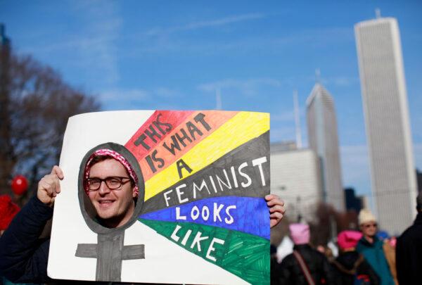 A man holds up a sign as he takes part in the Second Annual Womens March Chicago on Jan. 20, 2018. (Jim Young/AFP via Getty Images)