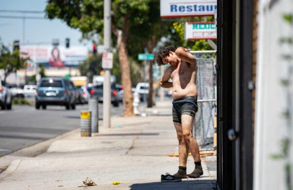 A homeless man contorts his body while working off a drug high in Santa Ana, Calif., on June 28, 2022. (John Fredricks/The Epoch Times)