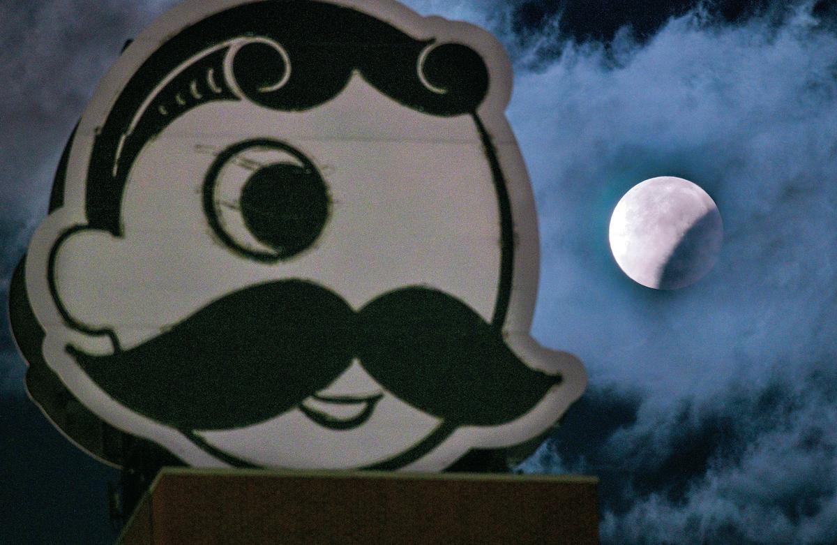The full beaver moon is seen in partial eclipse beyond an unlit Natty Boh on Baltimore's Brewers Hill in November 2021. (Jerry Jackson/Baltimore Sun/TNS)