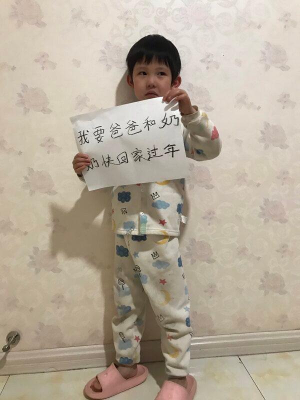 Gu Zhang's child holding a sign that reads "I want dad and grandma to come home soon to celebrate Chinese New Year." (Courtesy of Shuzhi Kang)
