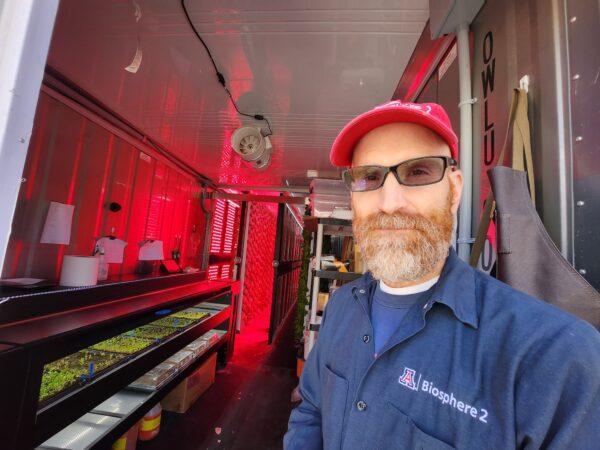 Biosphere 2 research specialist Jason Deleeuw displays the vertical freight farm in red light to aid in plant growth on Jan. 11, 2023. (Allan Stein/The Epoch Times)