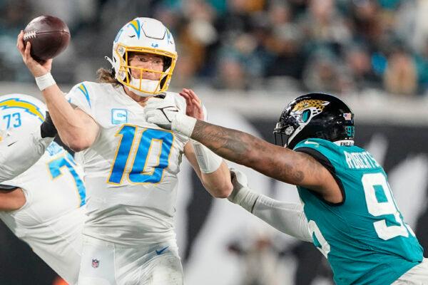 Los Angeles Chargers quarterback Justin Herbert (10) works in the pocket as Jacksonville Jaguars defensive end Roy Robertson-Harris (95) defends during the second half of an NFL wild-card football game in Jacksonville, Fla., on Jan. 14, 2023. (Chris Carlson/AP Photo)