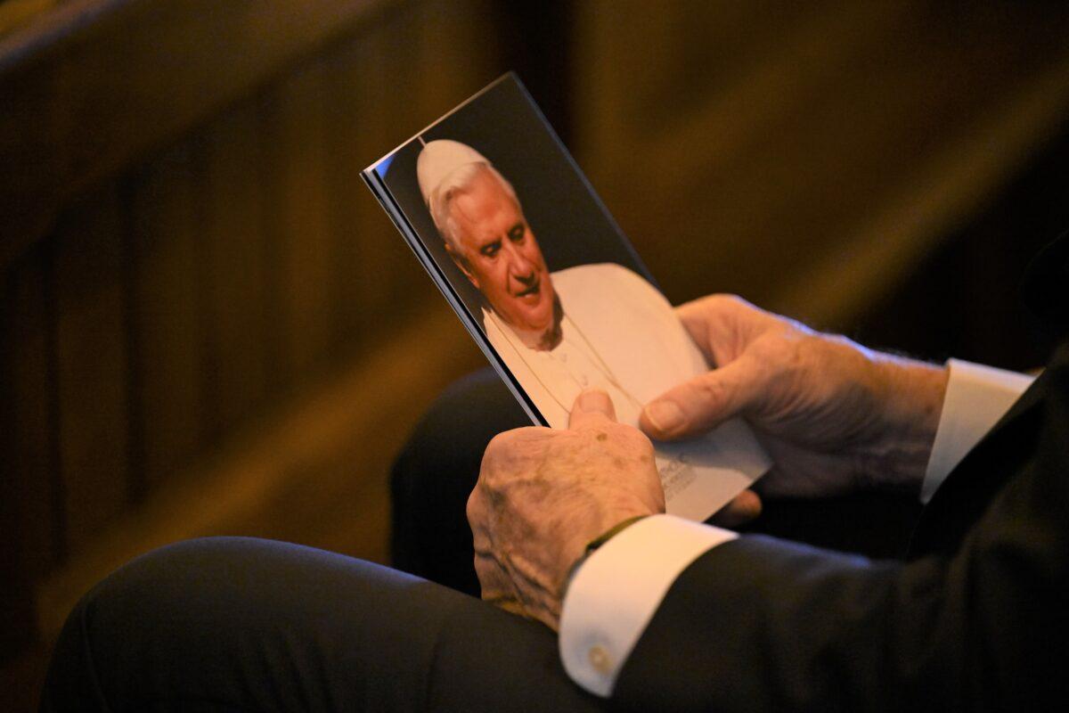 A parishioner holds a photo of Pope Benedict VXI and attends a Solemn Pontifical Requiem mass to pay homage to Cardinal George Pell at St Mary’s Cathedral in Sydney, Australia, on Jan. 12, 2023. (AAP Image/Dean Lewins)