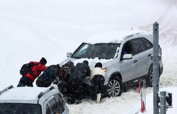 People push a vehicle in snow on a highway in Gangwon Province's Pyeongchang, about 126 kilometers (78 miles) east of Seoul, South Korea, on Jan. 15, 2023. (Yoo Hyung-je/Yonhap via AP)