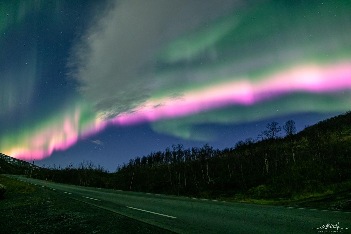 A pink ribbon of aurora borealis appears along a backroad on Nov. 2, 2022. (Courtesy of <a href="https://www.facebook.com/greenlandertromso">Markus Varik</a>)