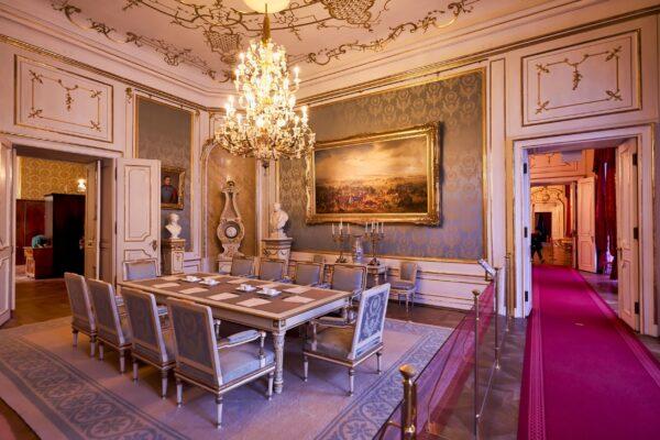 The conference room, also located in the Imperial apartments, is a more discreet approach to the baroque style. A gold crystal chandelier hangs down the ceiling and stucco work and gilding ornate the walls and door frames. Blue is the central color here, present throughout the elegant blue-and-silver carpet, wall tapestry, and chairs. (<a href="https://www.shutterstock.com/g/marcobriviophoto">marcobrivio.photo</a>/<a href="https://www.shutterstock.com/image-photo/kaiserappartements-hofburg-imperial-palace-sissi-vienna-1599936241">Shutterstock</a>)