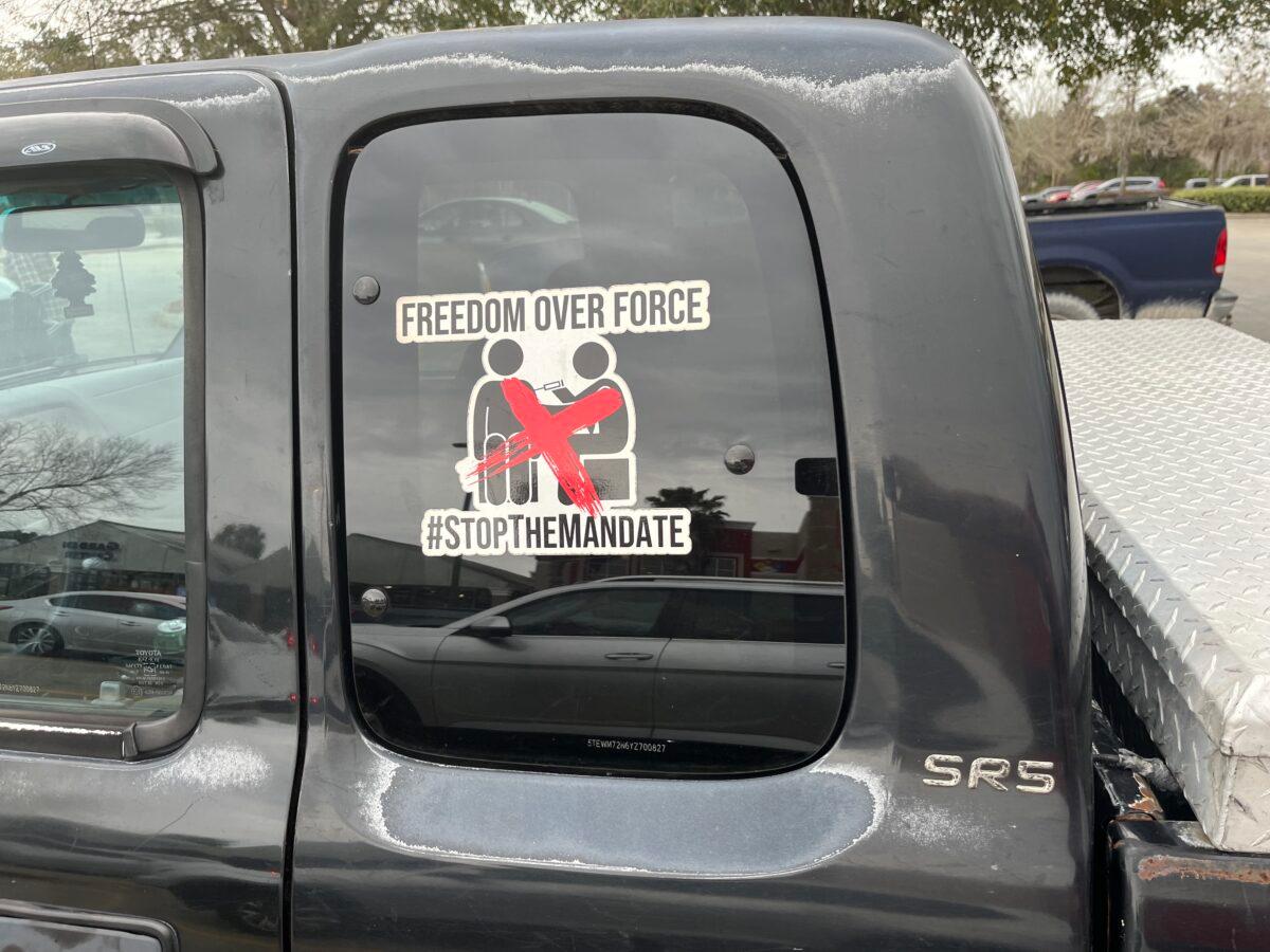 A sticker on the window of a pickup truck expresses disdain for vaccine mandates in Gainesville, Fla., on Jan. 21, 2023. City employees successfully challenged a vaccinate-or-terminate policy during the COVID-19 pandemic response. (Nanette Holt/The Epoch Times)