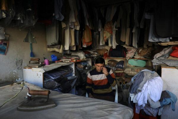 A laundryman uses a cell phone as he sits at his shop during a countrywide power breakdown in Peshawar, Pakistan, on Jan. 23, 2023. (Fayaz Aziz/Reuters)