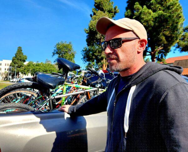Robert Reynolds, a veterans advocate with American Veterans Post 2 in Los Angeles, helps distribute bicycles to homeless veterans in Brentwood, Calif., on Jan. 16, 2023. (Allan Stein/The Epoch Times)