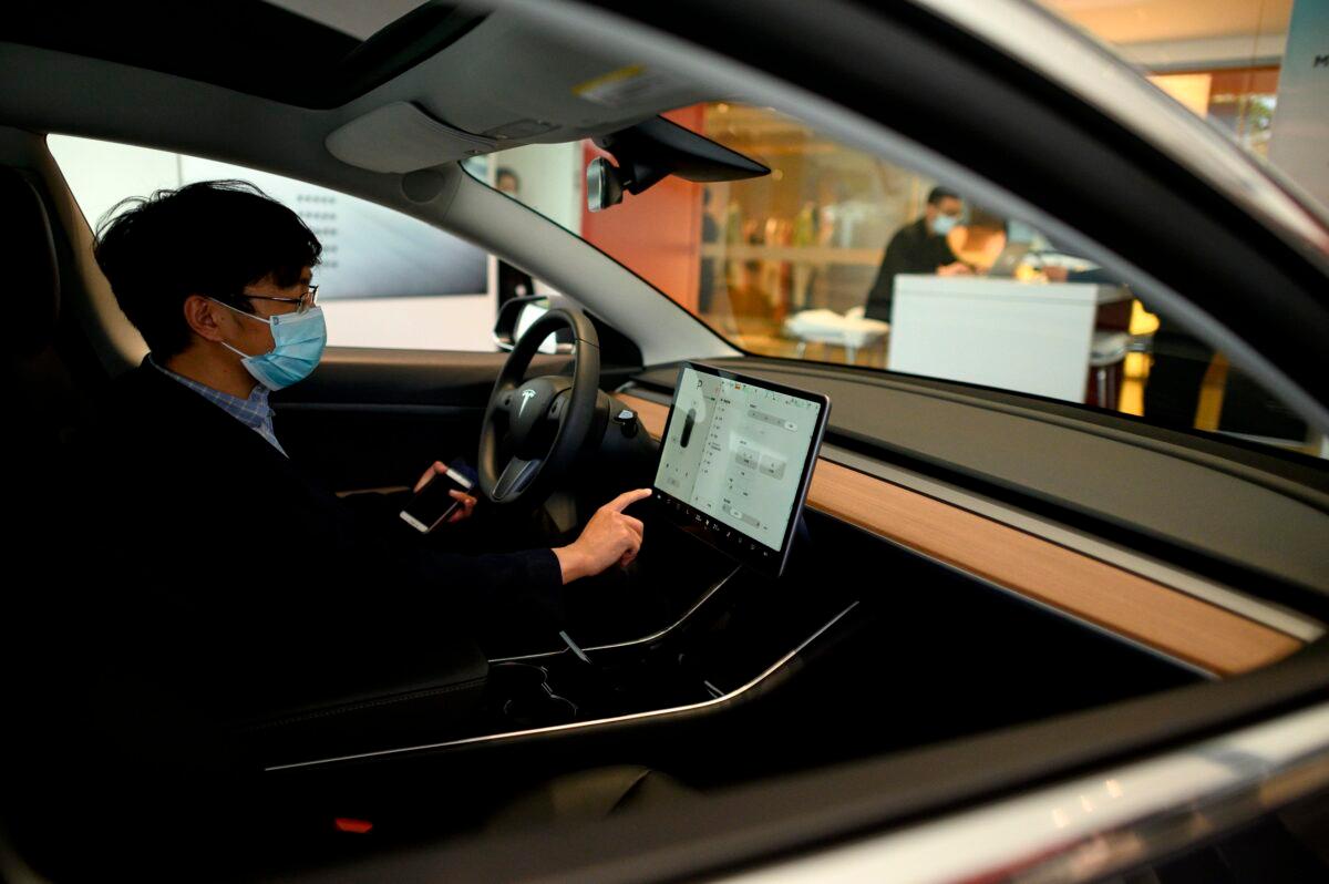 A customer checking a dashboard touch screen in a Tesla car on display at a showroom in Beijing on May 10, 2020. (Noel Celis/AFP via Getty Images)
