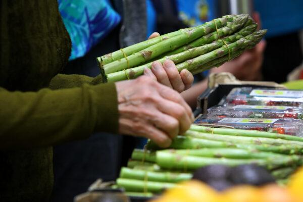 A shopper holds asparagus spears at Paddy's Market in Sydney, Australia, on Oct. 22, 2022. (Lisa Maree Williams/Getty Images)