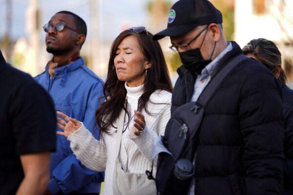 A woman holds her arms up in prayer as members of the community hold a prayer vigil near the scene of a shooting that took place during a Chinese Lunar New Year celebration, in Monterey Park, Calif., on Jan. 22, 2023. (Allison Dinner/Reuters)
