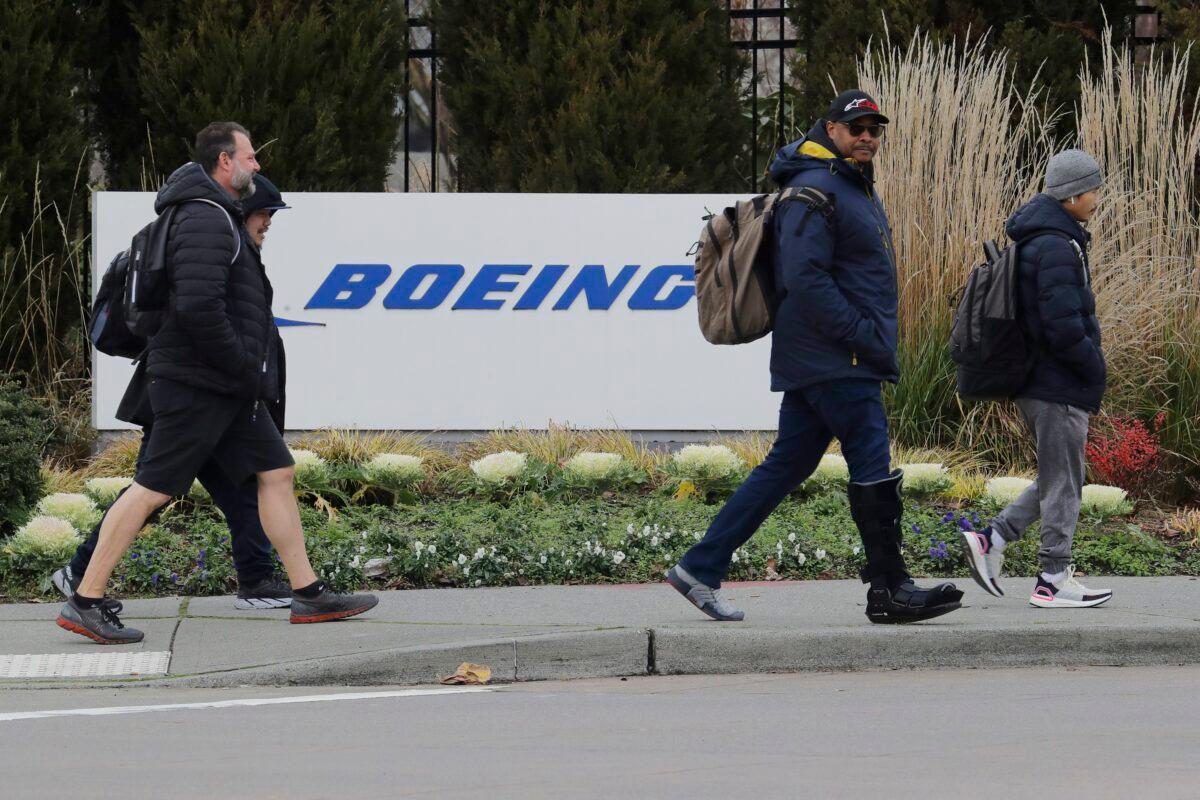 Workers walk past a Boeing Co. sign as they leave the factory where the company's 737 Max airplanes are built in Renton, Wash., on Dec. 17, 2019. (Ted S. Warren/AP Photo)