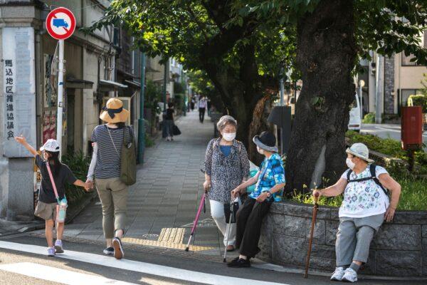 Elderly women chat along a street while a mother walks with her child in Tokyo's Minami-Magome area on July 20, 2021. (Charly Triballeau/AFP via Getty Images)