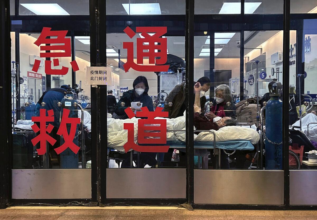 Patients and caregivers are seen in the closed entranceway of an emergency room being used as an overflow area at a hospital in Shanghai on Jan. 14, 2023. (Kevin Frayer/Getty Images)